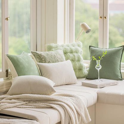 Verschiedene Kissen von Interior by Hakito, darunter das Kissen Dirk 2er Set in grünen und creme-weißen Tönen, ideal für eine gemütliche Fensterbank.