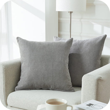 Zwei graue Kissen Nino von Interior by Hakito auf einem modernen Sofa, die einen eleganten Touch bringen und im 2er Set erhältlich sind.