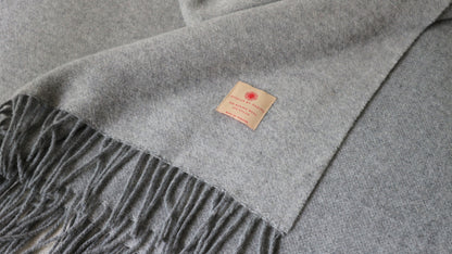 Nahaufnahme der grauen Merino Wolle Tagesdecke 140x200 cm von Interior by Hakito, die weiche Textur und Fransen zeigen.