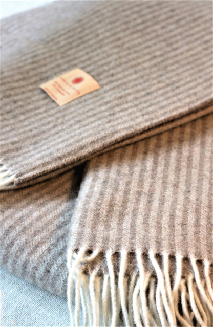 Nahaufnahme der Luxus-Tagesdecke von Interior by Hakito, aus Merinowolle und Kaschmir, zeigt das stilvolle Streifenmuster und die weiche Textur.