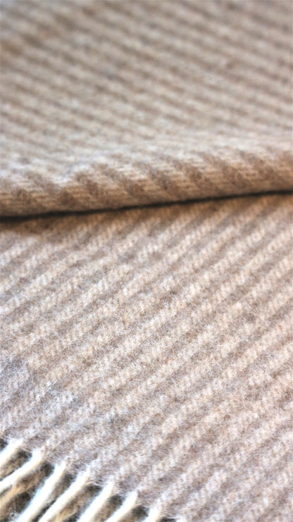Detailaufnahme einer Luxus Tagesdecke aus 90% Merinowolle und 10% Kaschmir mit elegantem Streifenmuster von Interior by Hakito, weich und stilvoll.