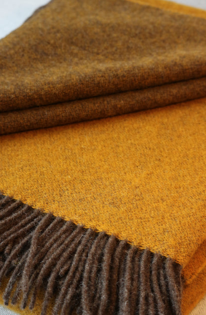 Gefaltete Robuste Lammwolle Tagesdecke von Interior by Hakito in warmen Braun- und Gelbtönen, perfekt für entspannte Momente.