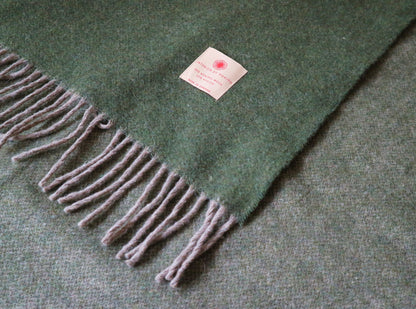 Details der Warme Merino Wolle Tagesdecke von Interior by Hakito in Olivgrün, zeigt die hochwertigen Fransen und das stilvolle Design, perfekt für jedes Wohnambiente.