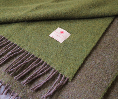 Ansprechende Darstellung einer robusten Lammwolle Tagesdecke von Interior by Hakito, in verschiedenen Grüntönen, ideal für komfortable Abende zuhause.