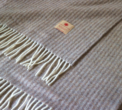 Luxus Tagesdecke aus Merinowolle und Kaschmir, markiert mit Etikett, auf einem hellen Hintergrund, von Interior by Hakito, sieht elegant und gemütlich aus.