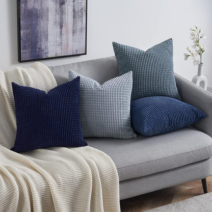 Vielseitige Kissen von Interior by Hakito im Modell Sven Kordsamt, perfekt für Sofa oder Stuhl, in harmonischen Blautönen auf einem modernen grauen Sofa.